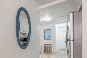 Eine moderne Küche mit weißen Schränken, einem blauen Spiegelrahmen, einem Edelstahlkühlschrank und einem gerahmten Bild an der Wand.