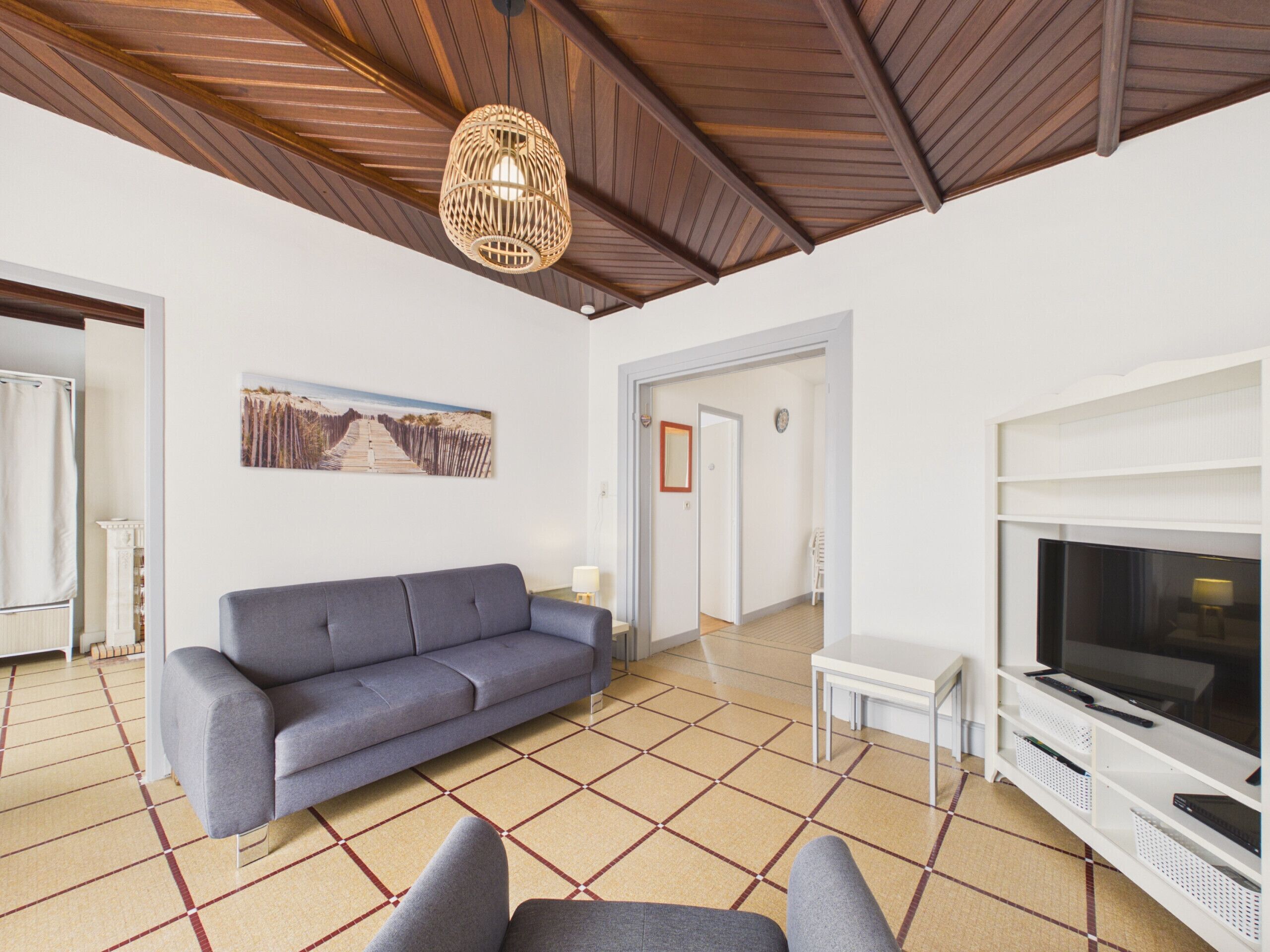 A living room with a sofa, a television, and a patterned floor.