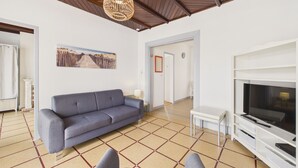 A living room with a sofa, a television, and a patterned floor. - Beach 100m away, apartment with terrace for 4 (Longeville-sur-Mer)