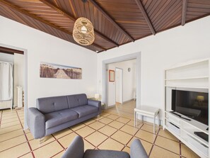 A living room with a sofa, a television, and a patterned floor. - Beach 100m away, apartment with terrace for 4 (Longeville-sur-Mer)