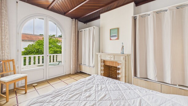 A bedroom with a bed, a chair, a fireplace, and a view of the outside. - Beach 100m away, apartment with terrace for 4 (Longeville-sur-Mer)