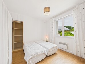 A bedroom with a bed, a bedside table, a window with a view, and a wardrobe. - Beach 100m away, apartment with terrace for 4 (Longeville-sur-Mer)