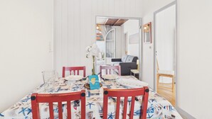 A dining area with a table set for two, chairs, a hanging light fixture, and a doorway leading to another room. - Beach 100m away, apartment with terrace for 4 (Longeville-sur-Mer)