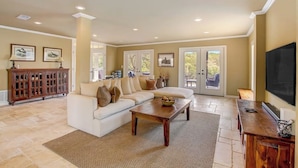 A living room with a sofa, coffee table, and a television. - Countryside 3-story home with game room, WFH office & guest house with kitchen (Volente)