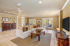 A living room with a sofa, coffee table, and a television. - Countryside 3-story home with game room, WFH office & guest house with kitchen (Volente)