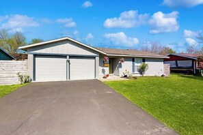 Ein eingeschossiges Haus mit Garage, Rasen und blauem Himmel.
