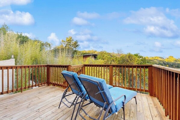 A wooden deck with two blue lounge chairs and a view of trees and hills. - Peaceful retreat on Lake Travis with amazing views near wineries & distilleries (Lakeway)
