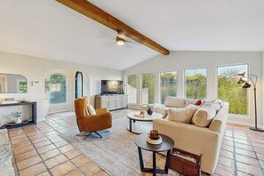 Een ruime woonkamer met een bank, fauteuil, salontafel en een open haard.