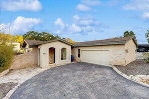 A single-story house with a garage, a driveway, and a small garden area. - Peaceful retreat on Lake Travis with amazing views near wineries & distilleries (Lakeway)