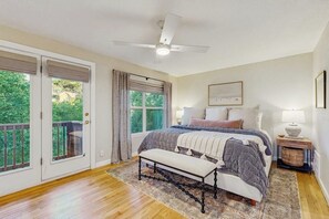 A bedroom with a bed, bench, ceiling fan, and a view through a door. - Peaceful retreat on Lake Travis with amazing views near wineries & distilleries (Lakeway)