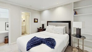 A hotel room with a bed, bedside tables, a bookshelf, and a door leading to a bathroom. - Charming, dog-friendly townhouse w/private gas grill, patio, & near downtown (Austin)