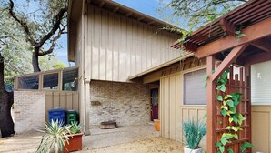 A two-story building with a brick exterior, a wooden pergola, and potted plants. - Charming, dog-friendly townhouse w/private gas grill, patio, & near downtown (Austin)
