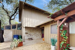 Ein zweistöckiges Gebäude mit Ziegelaußenwand, einer Holzpergola und Topfpflanzen.