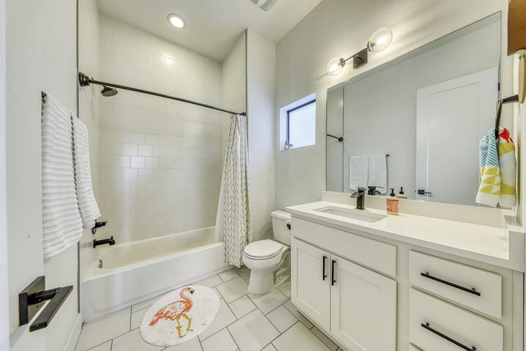 A bathroom with a bathtub, toilet, and vanity with a mirror.