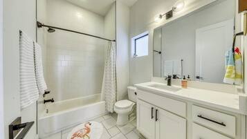 A bathroom with a bathtub, toilet, and vanity with a mirror.