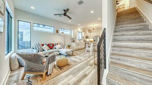 A spacious living area with a sofa, chairs, and a staircase.