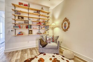 A cozy living room with a grey sofa, a cowhide rug, a bookshelf, and a lamp.