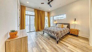A bedroom with a bed, a ceiling fan, a nightstand, a window, and a view of the outside.