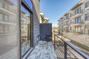 A balcony with a view of adjacent buildings, a small table, and two chairs.