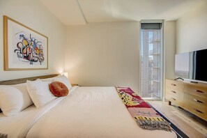Une chambre d’hôtel avec un lit, une télévision, une fenêtre donnant sur un paysage agréable et un tableau au mur.