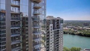 Een hoog gebouw met meerdere balkons, uitzicht op een rivier en een heldere lucht.