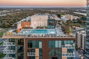 Un bâtiment moderne doté d’une piscine sur le toit, de grandes fenêtres et offrant une vue sur le paysage urbain environnant.