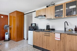A compact kitchen with wooden cabinets, a built-in stove, a microwave, and a sink.