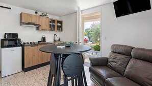 Um espaço de estar compacto com cozinha compacta, mesa de jantar e sofá de couro.