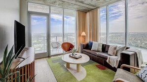 Uma sala de estar moderna com uma janela ampla, televisão de tela plana, sofá, mesa de centro e uma planta.