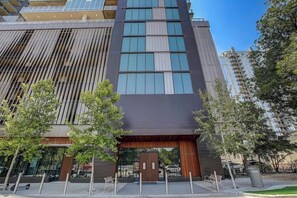 Un bâtiment moderne à la façade sombre, doté de grandes fenêtres et d’une entrée en bois.