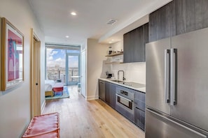 A modern kitchen with a large stainless steel refrigerator, a built-in oven, and a window overlooking a cityscape. - Austin Rainey Street studio - lake & skyline-view balcony, rooftop pool & gym (Austin)