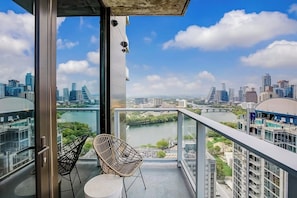 A balcony with a city view, two wicker chairs, and a table. - Austin Rainey Street studio - lake & skyline-view balcony, rooftop pool & gym (Austin)