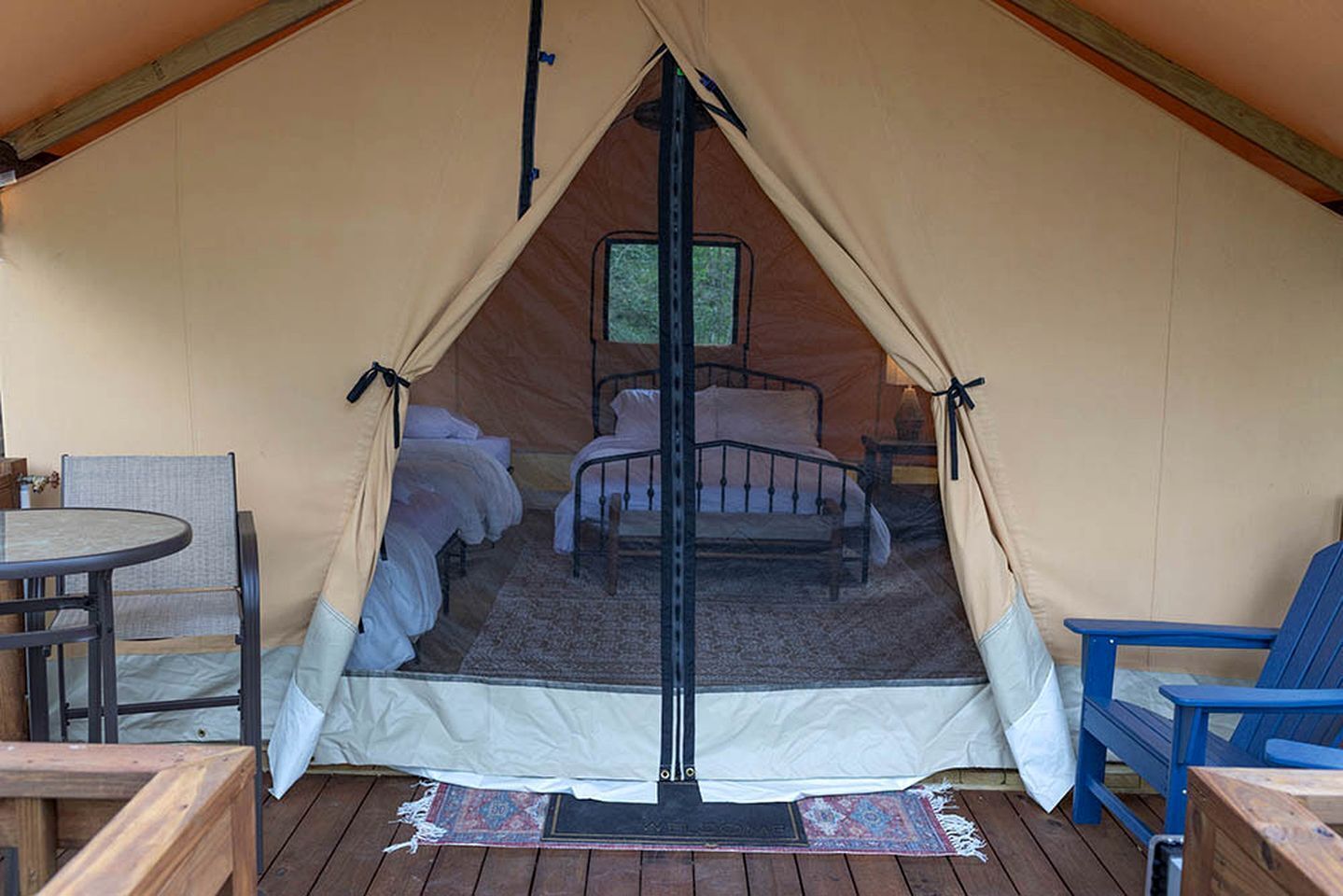 A tent with a bed, a table, and chairs inside.