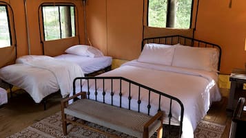 A tent-style room with two beds, a bench, and a small table.