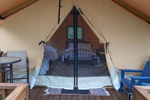 A tent with a bed, a table, and chairs inside.