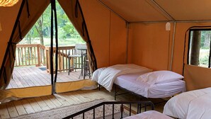 A tent with two beds, a wooden deck, and a table outside. - Great Small Group Safari Tent in Livingston, Texas (Livingston)
