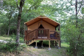 A wooden cabin with a balcony, surrounded by trees.