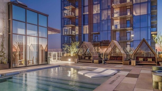 Un edificio moderno con piscina, area relax all'aperto e facciata in vetro.