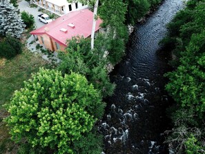 A building with a red roof, surrounded by dense greenery and a river.