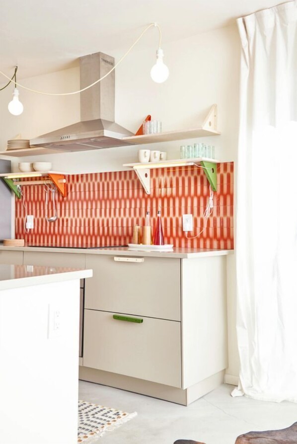A kitchen with a striped backsplash, a built-in stove, and a hanging light fixture.
