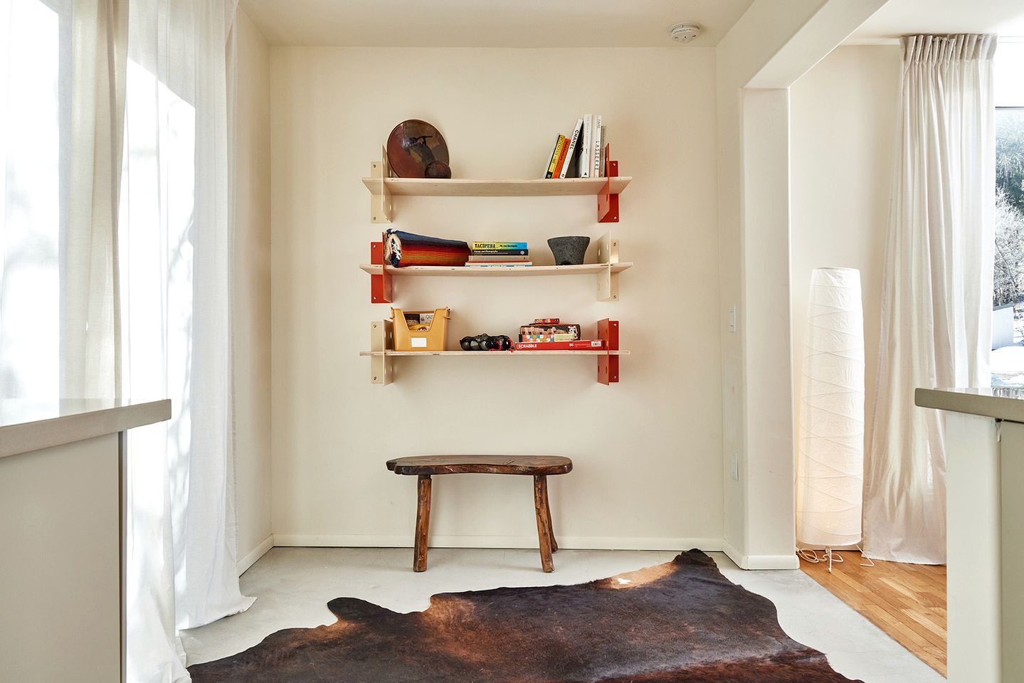 A room with a bookshelf, a small stool, and a cowhide rug.