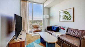 A modern hotel room with a flat-screen TV, a sofa, a coffee table, and a large window offering a city view. - Austin hideaway in the heart of the city with rooftop pool, terrace, and gym (Austin)