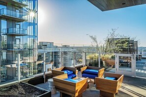 Eine Dachterrasse mit Glaswänden, Sitzmöglichkeiten im Freien und Blick auf die Stadtlandschaft.