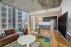 Ein modernes Apartment mit Wohnzimmer, Küche und großen Fenstern.