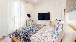 A bedroom with a bed, a TV, a ceiling fan, a mirror, and a window. - Modern two story home with kitchen, gated yard, balcony, close to South Congress (Austin)