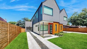 A modern two-story house with a garage, a covered porch, and a well-maintained lawn. - Fantastic townhouse with enclosed backyard and high-speed internet (Austin)