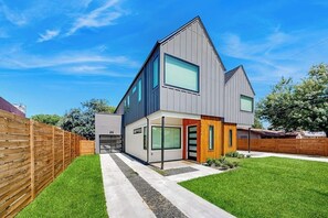 Ein modernes, zweistöckiges Haus mit Garage, überdachter Veranda und gepflegtem Rasen.