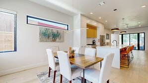 A modern kitchen with white cabinetry, a central island, and a dining area with white chairs. - Fantastic townhouse with enclosed backyard and high-speed internet (Austin)