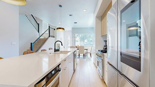 A modern kitchen with a central island, stainless steel appliances, and a staircase leading to another level. - Fantastic townhouse with enclosed backyard and high-speed internet (Austin)