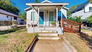 A single-story house with a front porch, a small staircase, and a wooden fence. - Modern cozy house with full kitchen, dining & living area, TV, close to downtown (Austin)